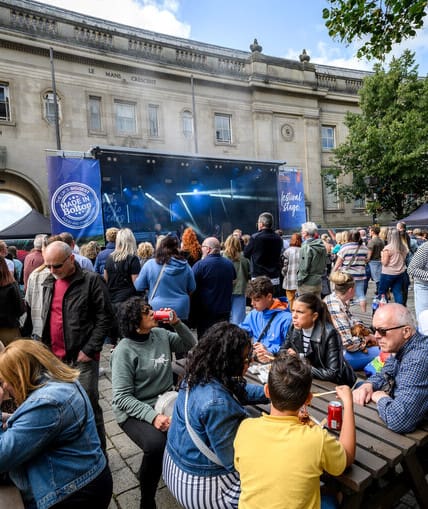 Large crowd of people around a music stage in Bolton